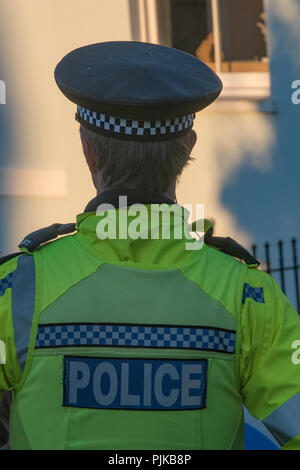 Polizei bei einer Veranstaltung den Frieden tragen ein helles Gelb hohe Sichtbarkeit Jacke und Polizei Schirmmütze. Stockfoto