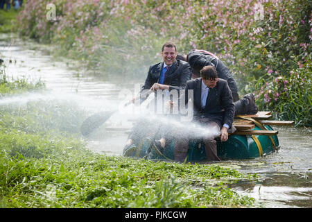 Drei tragen schwarze Anzüge Nass aus einem Schlauch, der auf einem Floß Ein Fluß im Tiefland Spiele, Thorney, Somerset, England Stockfoto