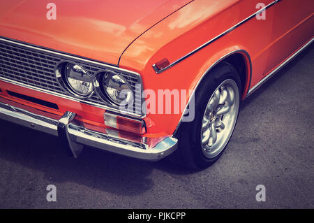 Alte Oldtimer Farbe orange auf dem grauen Asphalt auf der Straße. Scheinwerfer Nahaufnahme. Stockfoto