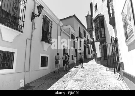 Eine Familie laufen in Sandalen, eine schmale gepflasterte Straße an einem sonnigen Tag in Ronda Andalusien Spanien Stockfoto