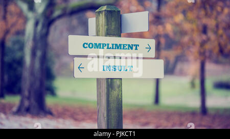 Retro Vintage Style Bild einer ländlichen Schild mit zwei Zeichen sagen - Kompliment - Beleidigung - das Zeigen in entgegengesetzte Richtungen. Stockfoto