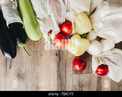 Gemüse in eco Baumwolle Taschen am Tisch in der Küche, null Abfall Shopping. Flach. Pilze, Zucchini, Auberginen, Paprika, Tomaten, Nektarinen auf Holz Stockfoto