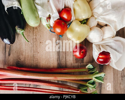 Gemüse in eco Baumwolle Taschen am Tisch in der Küche, null Abfall Shopping. Flach. Pilze, Zucchini, Auberginen, Paprika, Tomaten, Nektarinen auf Holz Stockfoto