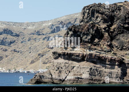 Griechenland, die charmante Insel Thirasia. Dramatische vulkanische Felsformationen. Blick auf schroffe, zerklüftete Klippen, die aus der Ägäis emporragen. Stockfoto