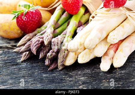 Grünen und weißen Spargel, Erdbeeren und Kartoffeln auf Holzbrett Stockfoto