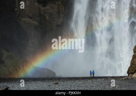 Europa, Nordeuropa, Island, Skógar, Paar vor der mächtigen Skógafoss im südlichen Island, Regenbogen Stockfoto