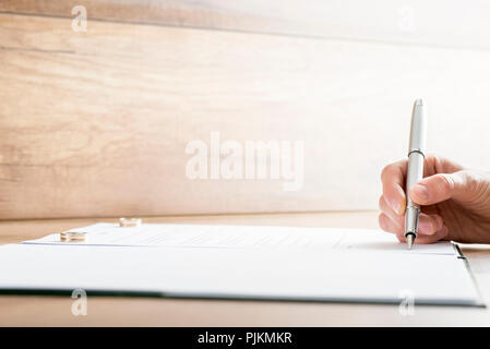 Unterzeichnung Ehe oder Scheidung mit zwei Trauringe jeden liegen auf der einen Seite des Dokuments. Stockfoto