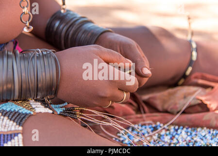 Frau Himba macht Schmuck, Close-up der Hände Stockfoto