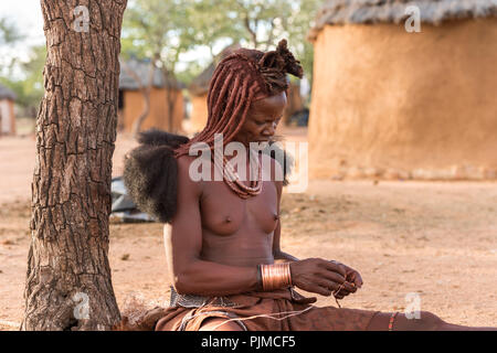 Frau Himba macht traditionellen Schmuck aus Rest Material und hausgemachte Perlen Stockfoto