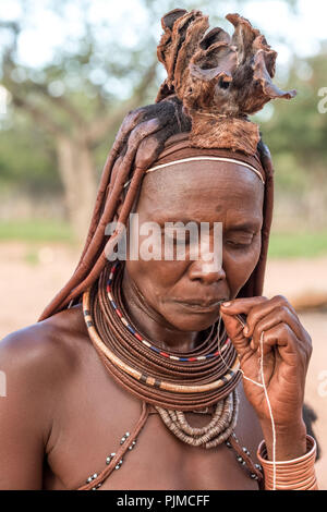 Frau Himba macht traditionellen Schmuck aus Rest Material und hausgemachte Perlen Stockfoto