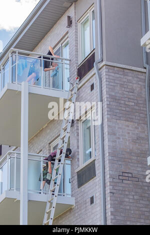 Zwei Männer reinigen Sie das Glas und Fenster eines Mehrfamilienhauses. Stockfoto