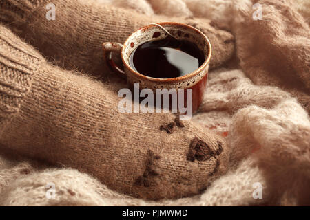 Gemütliche Winter Herbst Herbst Lifestyle: Frau feets Beine in warmen süssen Bär Socken und Tasse Tee. Retro, Tonisierung, beige Monochrom, hipster noch leben, Saison Stockfoto