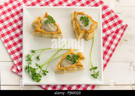 Vol-au-vents wie ein Weihnachtsbaum geformt, gefüllt mit Pilzragout und mit frischer Petersilie garniert Stockfoto