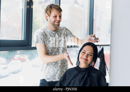 Junge Frau im Spiegel auf der Suche nach Haarschnitt. Stockfoto