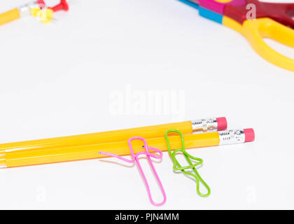 Zwei Büroklammern sprechen beim Liegen auf einem weissen Stock und auf einem Bleistift. Miniatur Schule leben und zurück in die Schule Konzept mit Kopie Raum weiß backgroun Stockfoto