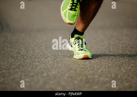 Beine Läufer in hellem Grün Laufschuhe auf dem Hintergrund der dunklen Asphalt Stockfoto