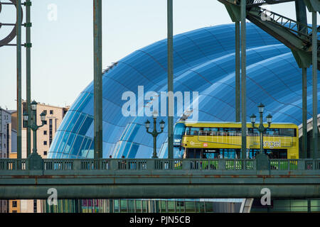 Newcastle, England - August 2, 2018: Bus Überqueren der Tyne Bridge und Konzerthalle Sage Gateshead im Hintergrund bei Newcastle Quayside im Sommer Stockfoto