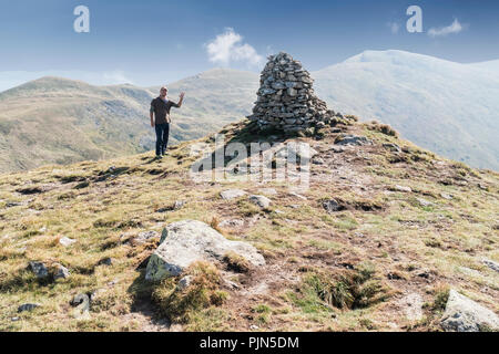 Mann seine Hand winken oben auf dem Berg in der Nähe des Damm der Steine Stockfoto