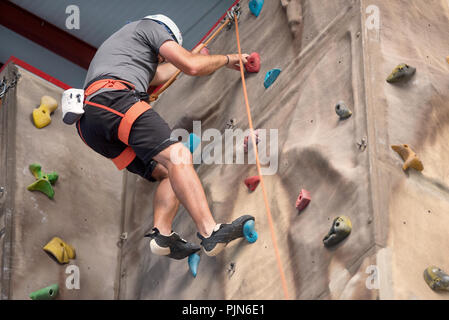 Junger Mann üben Klettern an künstlichen Wänden im Innenbereich. Stockfoto