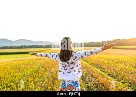 Junge Frau auf einem Feld, das Leben mit den Händen weit geöffnet. Stockfoto