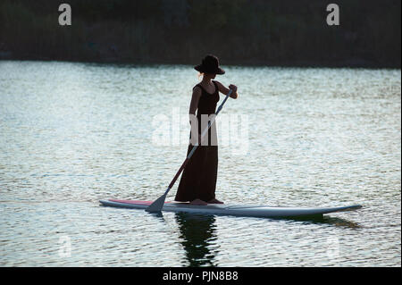 Stand Up Paddle Board von schönen Mädchen am Sonnenuntergang Hintergrund durchgeführt Stockfoto