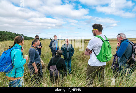 John Muir Country Park, Dunbar, East Lothian, Schottland, Großbritannien, 8. September 2018. Eine kleine Gruppe von Menschen genießen Sie einen Spaziergang und Gespräch von David Connelly von East Lothian Rat Archäologie Service Prüfung Nachweis der Weltkrieg defensive Positionen während East Lothian Archäologie und lokale Geschichte vierzehn Tage im September findet jedes Jahr statt und ist Teil der jährlichen Schottischen Archäologie Monat. Übersicht überwachsen Beweis des Ersten Weltkriegs Gräben in der Düne Bank Stockfoto