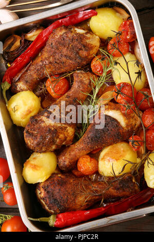 Gebratene Hähnchenkeulen mit Kartoffeln und Gemüse auf den Pan Stockfoto