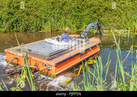 Ein kleiner Bagger ist mit klaren Sommer Unkrautbewuchs auf Grand Canal in der Nähe von Tiverton Westernm in North Devon verwendet. Stockfoto