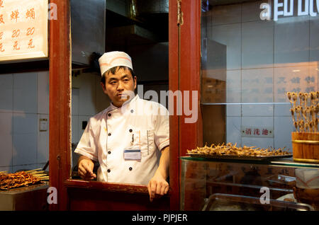 Peking, China - 1. Juni 2018: Koch in seinem weißen Uniform kochen traditionelles Chinesisch Essen auf Snack Street Food Markt in Peking in China. Stockfoto