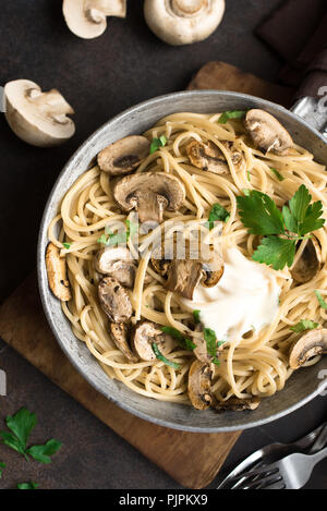 Pilz Spaghetti Pasta und Sauce auf rustikalen Hintergrund, Ansicht von oben, kopieren. Hausgemachte italienische Pasta mit Champignon Pilze in der Küche pan. Stockfoto