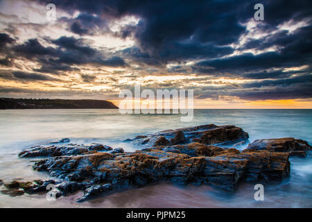 Sonnenuntergang über dem Strand von Tresaith, Ceredigion, Wales, in Richtung Aberporth. Stockfoto