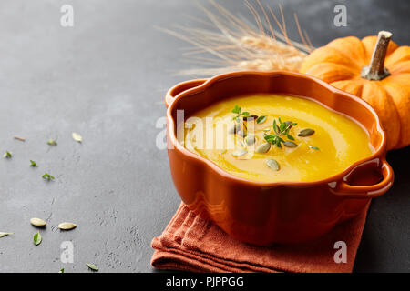 Kürbissuppe mit Thymian Kräuter-, Creme- und Kürbiskernen diente in orange Kürbis geformte Schale Stockfoto