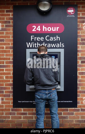 Junger Mann mit den 24 Stunden Tesco Dorf cashpoint Stockfoto