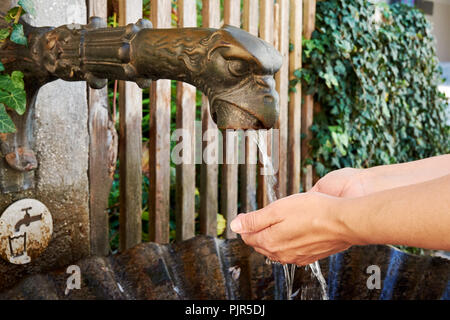 Eine Nahaufnahme eines Bronze Brunnen mit fließendem Wasser in Salzburg und ein trinken Frau ihre Hände waschen - Österreich in Europa Stockfoto