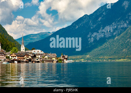 Blick auf die Stadt und den Hallstätter See in Österreich, der Alpen unter einem blauen Himmel mit Wolken und Wald im Hintergrund auf einem hellen und sonnigen Tag Stockfoto