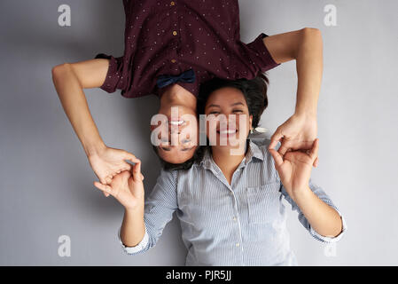 Junge glückliches Paar Liegen mit gefalteten Händen auf Grau studio Hintergrund isoliert Stockfoto