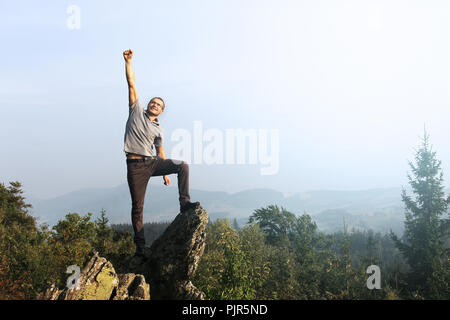 Glückliche Menschen mit Hand oben auf dem Gipfel des Berges mit einer schönen Aussicht. Sieg. Stockfoto