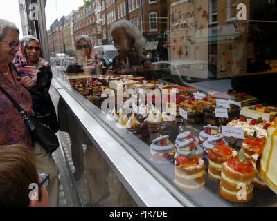 Leute schauen auf Kuchen durch eine Bäckerei Fenster Stockfoto