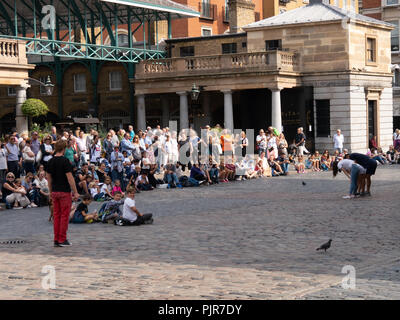 Massen von Menschen sehen eine Straße Leistung in Covent Garden, London, England Stockfoto