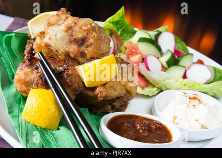 Ein tellergericht Huhn Karaage mit roter Chili bean Dip und Paprika Joghurt serviert mit Frischer gemischter Salat Stockfoto