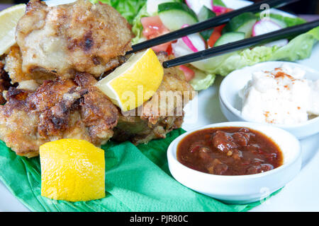 Ein tellergericht Huhn Karaage mit roter Chili bean Dip und Paprika Joghurt serviert mit Frischer gemischter Salat Stockfoto