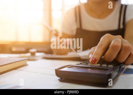 In der Nähe der weiblichen Hand tun, Finanzen und auf dem Schreibtisch über Kosten zu Hause Büro berechnen. Buchhalter oder Bankier und Berechnungen. Einsparungen, Finanzen ein Stockfoto