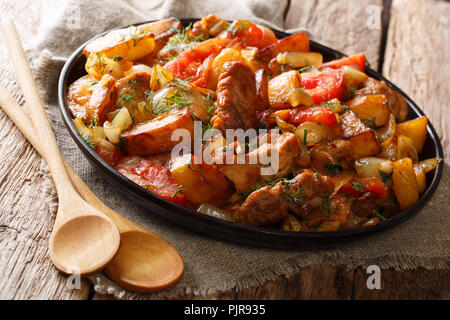 Georgische Abendessen: gebratenes Fleisch mit Kartoffeln, Tomaten, Zwiebeln, Kräutern und Gewürzen close-up auf eine Pfanne auf dem Tisch. Horizontale Stockfoto