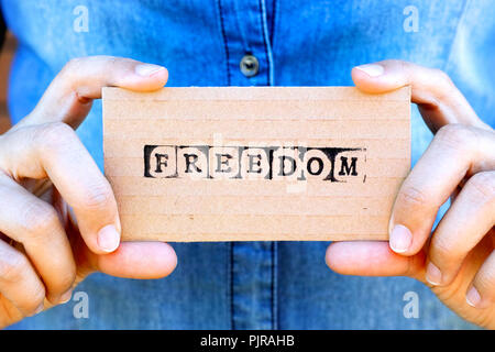 Frau hand Karton Karte mit Wort Freiheit durch schwarze Alphabet Briefmarken gemacht. Denim Hintergründe. Stockfoto