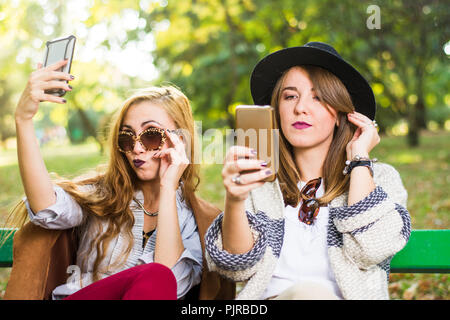 Weibliche Freunde klatschen mit einem Telefon im Park Stockfoto