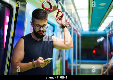 Mann mit smart phone unter Berücksichtigung der u-bahn Stockfoto
