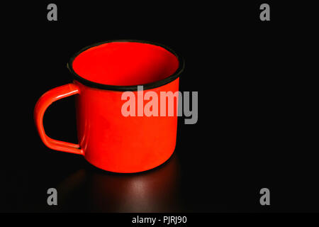 Orange Emaille Tasse auf einem schwarzen Hintergrund. Stockfoto