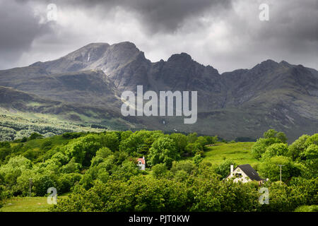 Sonne auf Bla Bheinn peak Ausreißer von Black Cuillin Hills unter dunklen Wolken aus dem schottischen Hochland Torrin Isle of Skye Schottland Großbritannien Stockfoto