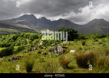 Dappled Sonne auf blaven Berge von Black Cuillin Hills unter dunklen Wolken aus dem schottischen Hochland Torrin Isle of Skye Schottland Großbritannien Stockfoto