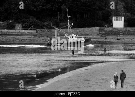 Eine kleine Fischerboote schiebt sich in Teignmouth Hafen durch das sich schnell bewegende Tidal race. Stockfoto